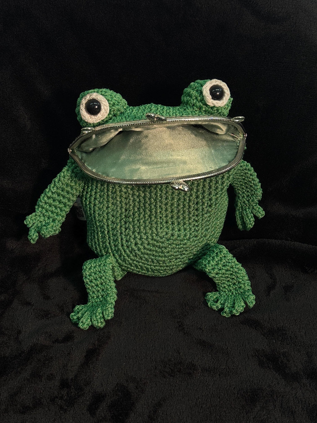 Front view of handmade green crochet frog bag with big eyes and metal clasp