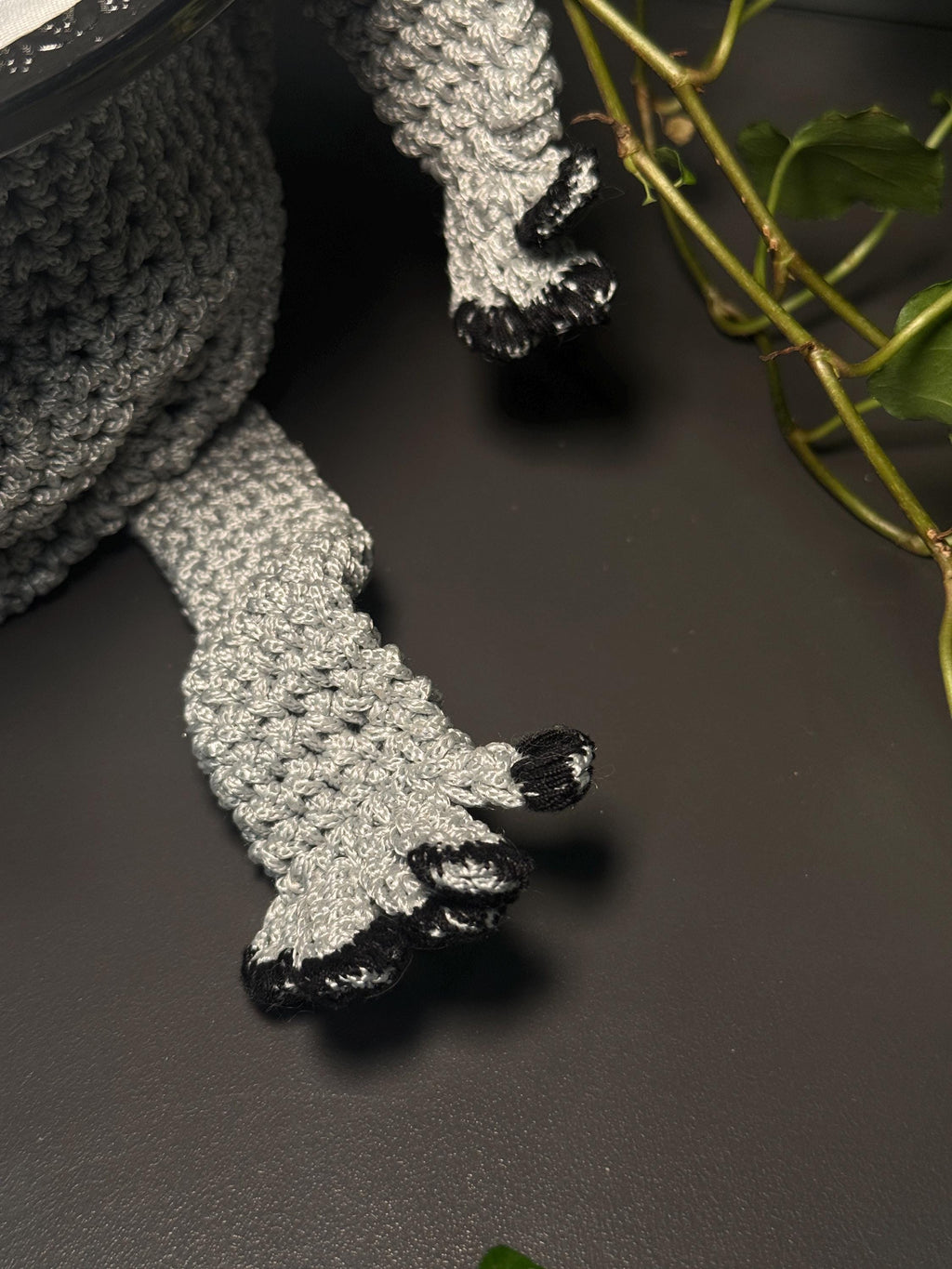 Close-up of gray crochet frog feet with black claws, showing detailed texture and craftsmanship