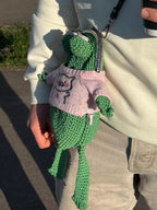 Green frog purse worn on shoulder with pastel pink frog hoodie